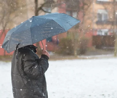 Muž stojí venku pod deštníkem.