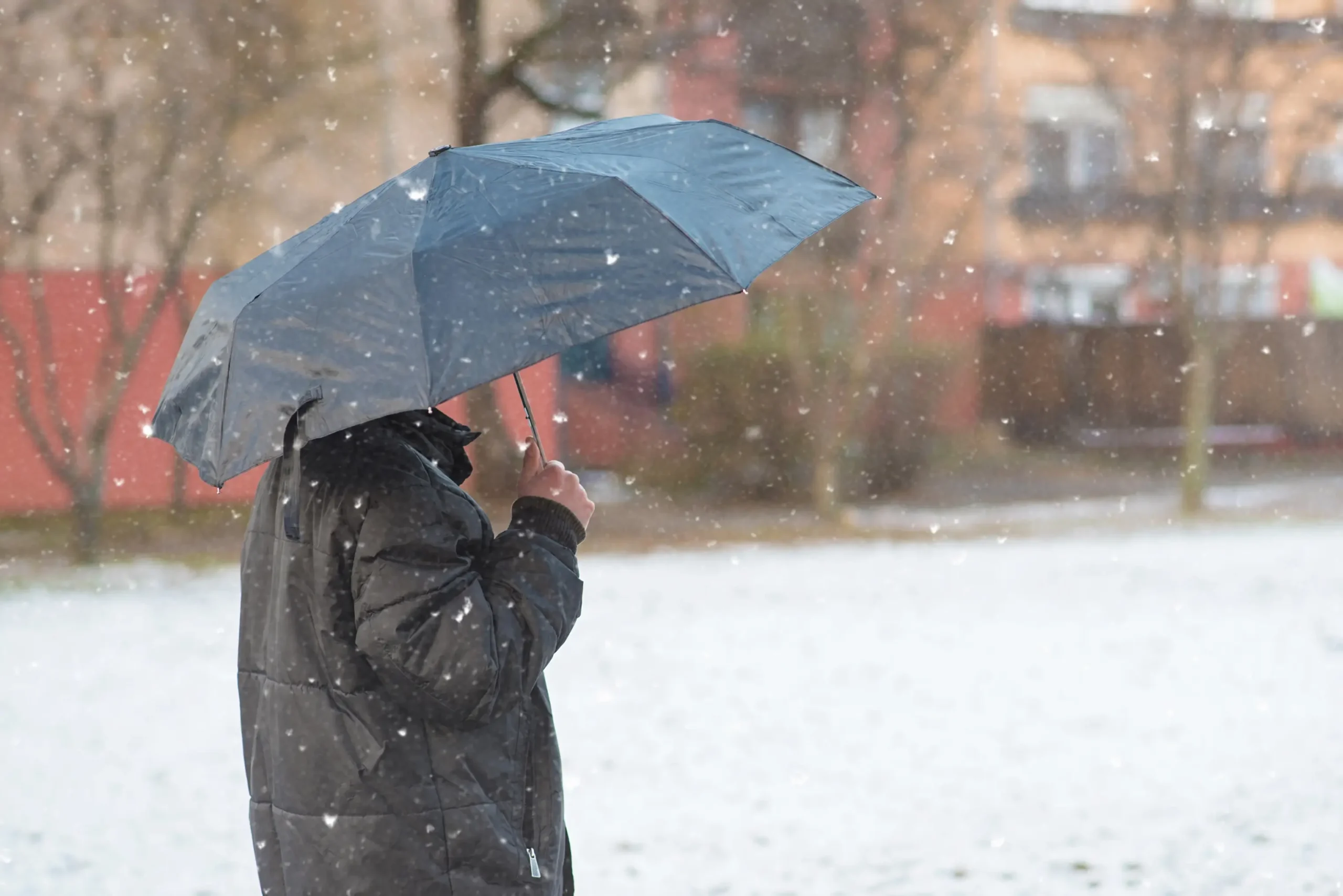 Muž stojí venku pod deštníkem.