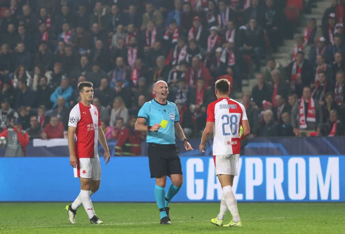 Na hřišti jsou hráči Slavie a rozhodčí. 