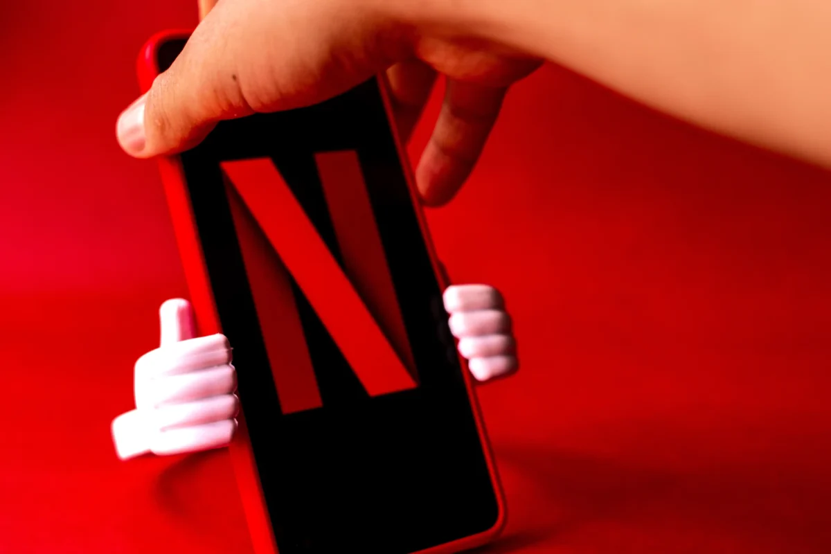 Člověk v ruce drží telefon s logem Netflixu. 