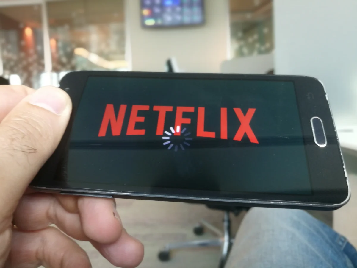Člověk v ruce drží telefon s Netflixem. 