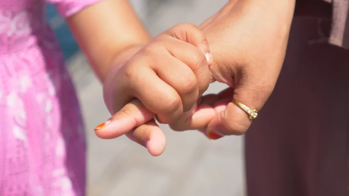 Holčička drží ženu za prst.