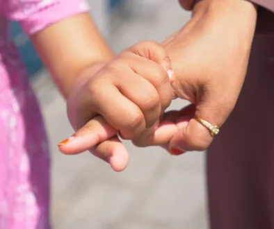 Holčička drží ženu za prst.