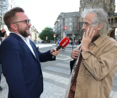 Oldřich Kaiser stojí u mikrofonu.
