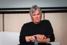Richard Dean Anderson sedí a tváří se naštvaně.