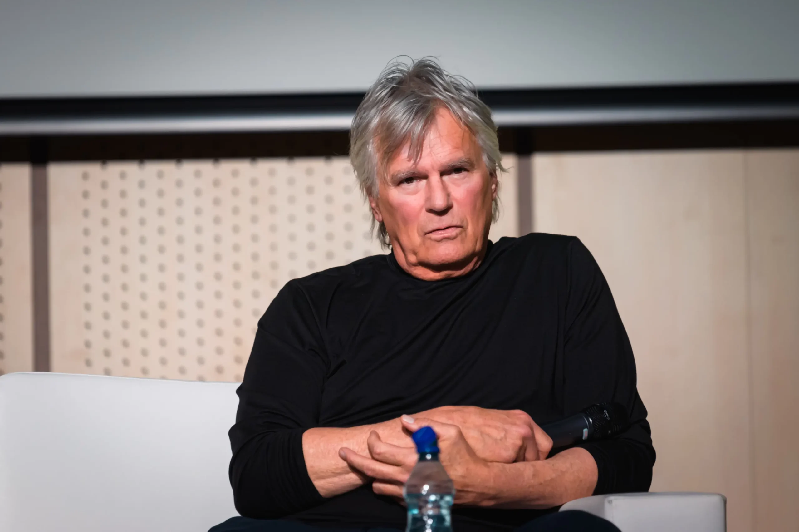Richard Dean Anderson sedí a tváří se naštvaně.