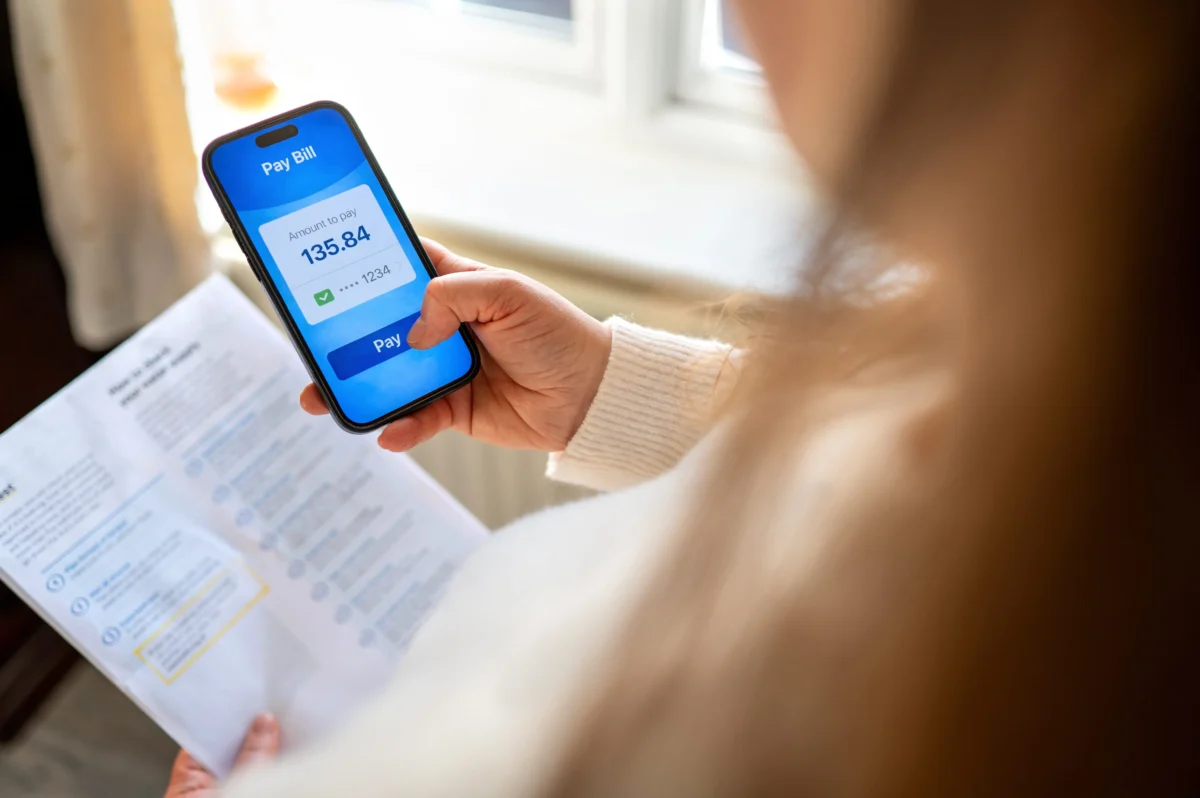 žena drží papír a mobilní telefon