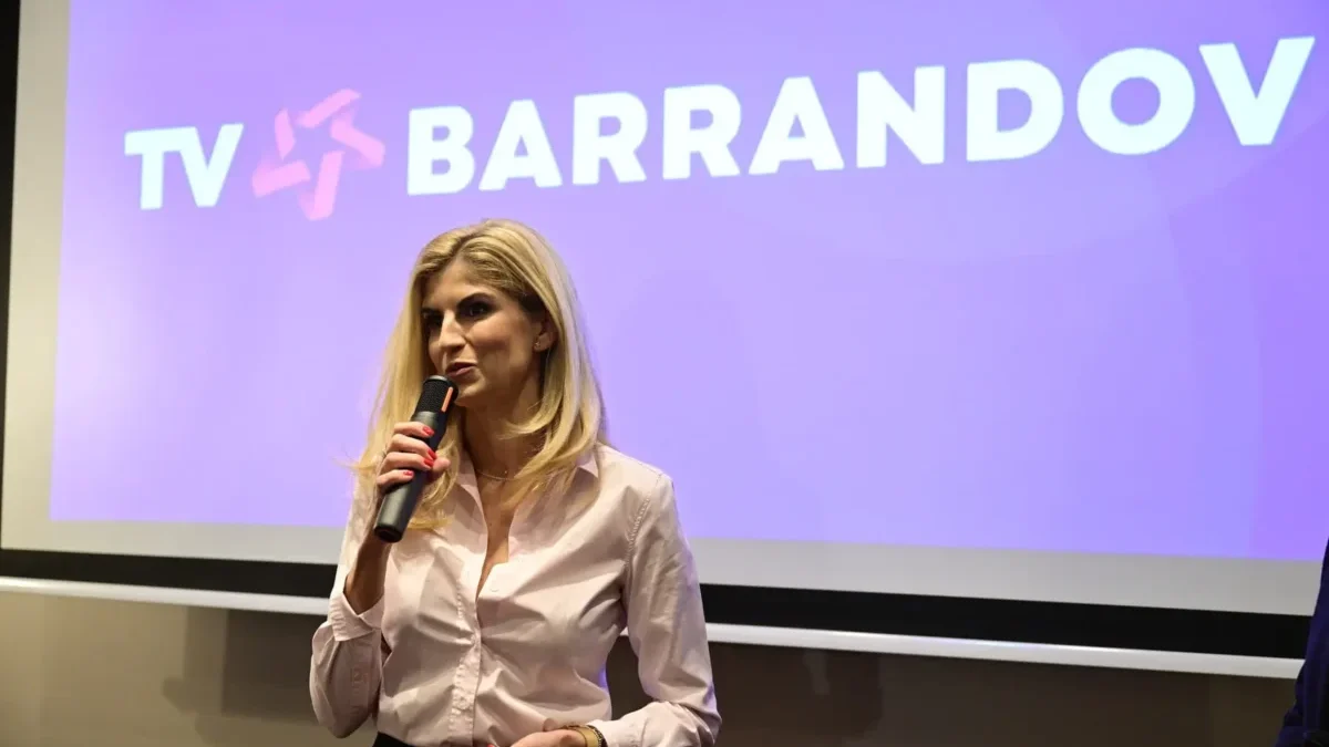žena s mikrofonem stojí před plátnem