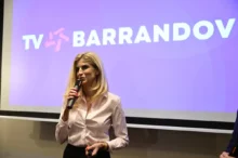 žena s mikrofonem stojí před plátnem