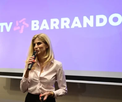 žena s mikrofonem stojí před plátnem