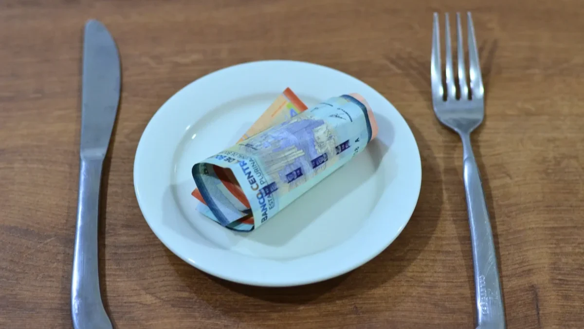 Na talíři leží srolovaná bankovka.