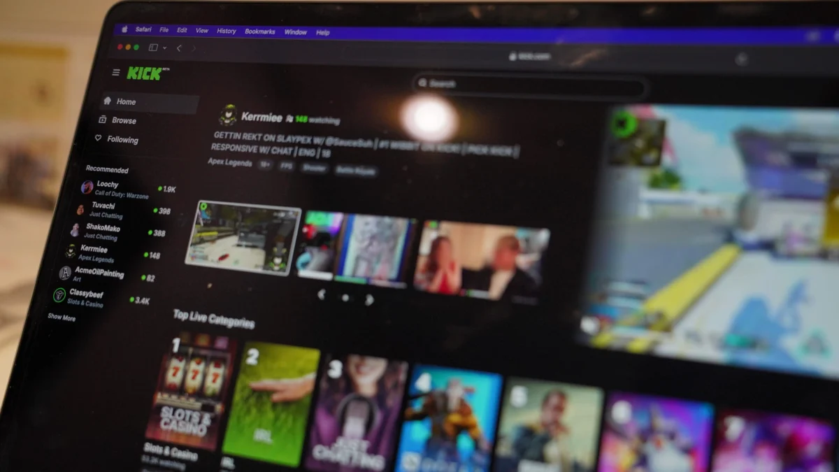 Close-up of a laptop screen showing a dark streaming platform UI with a left navigation menu (Home, Browse, Following) and a grid of colorful game thumbnails or videos across the main area.