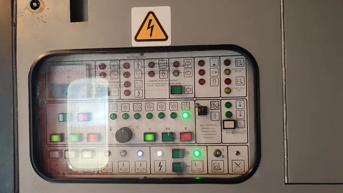 shutterstock_2692031513 1 | TVGURU.cz Industrial electrical control panel with a high-voltage warning sticker on the gray housing and illuminated buttons behind a glass window