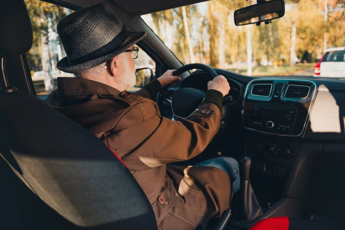 Starší muž řídící auto.