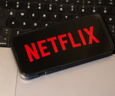 Na notebooku leží mobil s logem Netflixu.