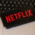 Na notebooku leží mobil s logem Netflixu.