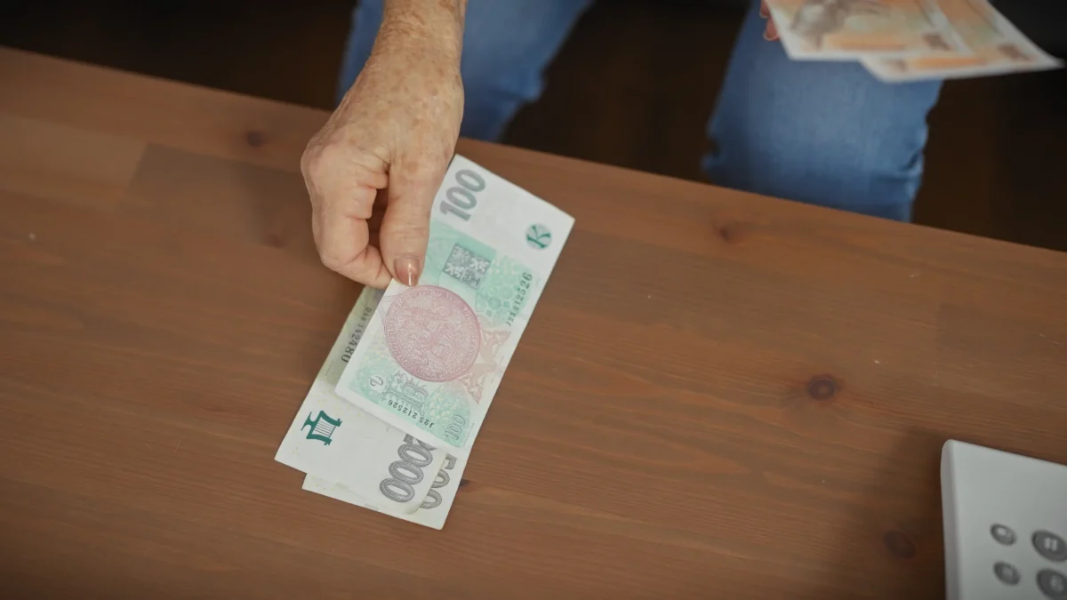 shutterstock_2474805375 | TVGURU.cz Žena na stůl pokládá bankovky.