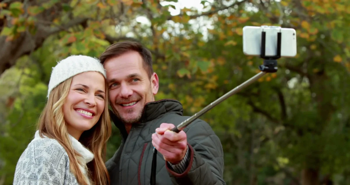Dva lidé se fotí selfie tyčí