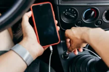 Člověk v autě drží mobil.