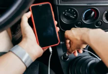 Člověk v autě drží mobil.