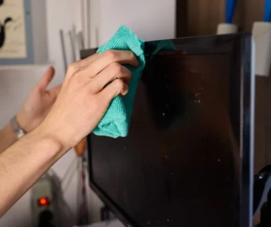 Člověk hadříkem otírá televizi.