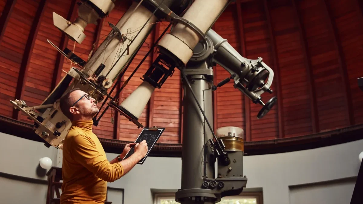 Astronom stojí u velkého teleskopu