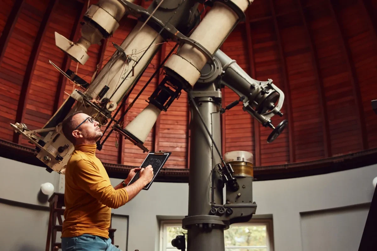 Astronom stojí u velkého teleskopu