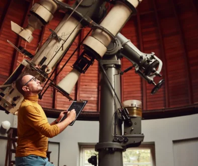 Astronom stojí u velkého teleskopu