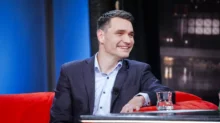 Moderátor Daniel Stach sedí na gauči.
