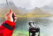 Fotograf v dešti s fotoaparátem u jezera