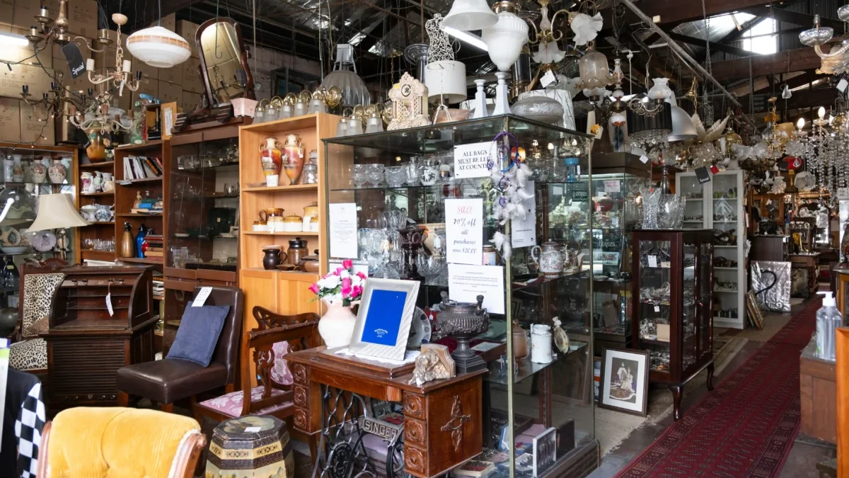 Antique shop interior filled with glass cabinets, chandeliers, vases, and wooden furniture