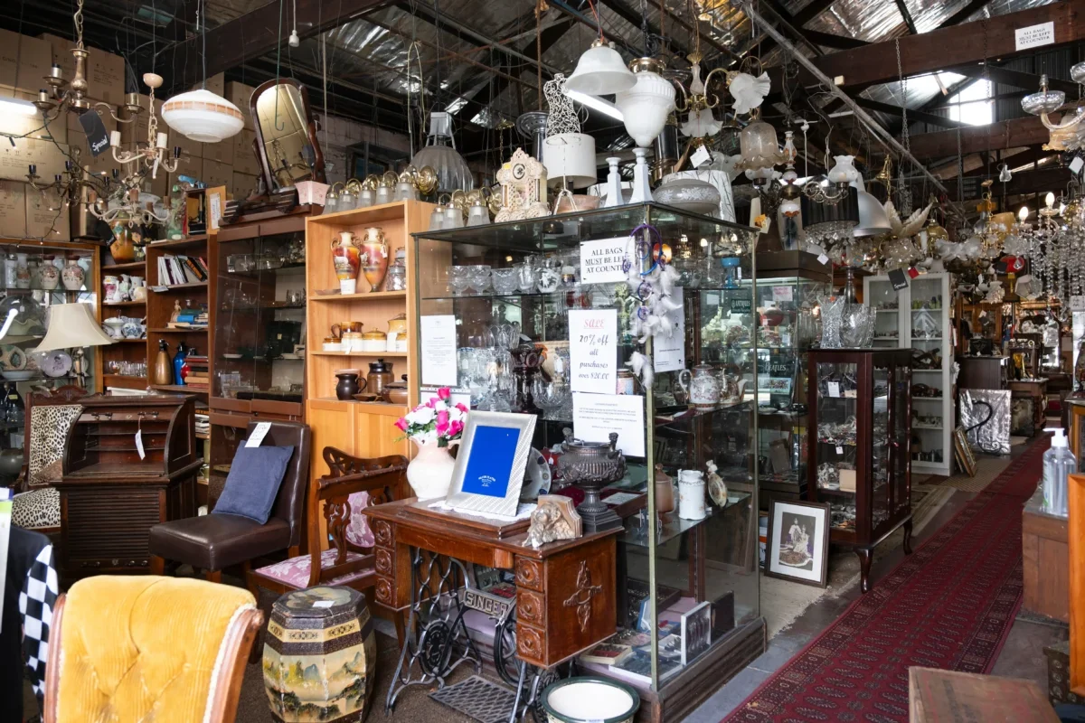 Antique shop interior filled with glass cabinets, chandeliers, vases, and wooden furniture