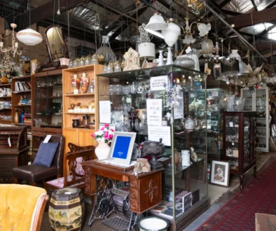Antique shop interior filled with glass cabinets, chandeliers, vases, and wooden furniture