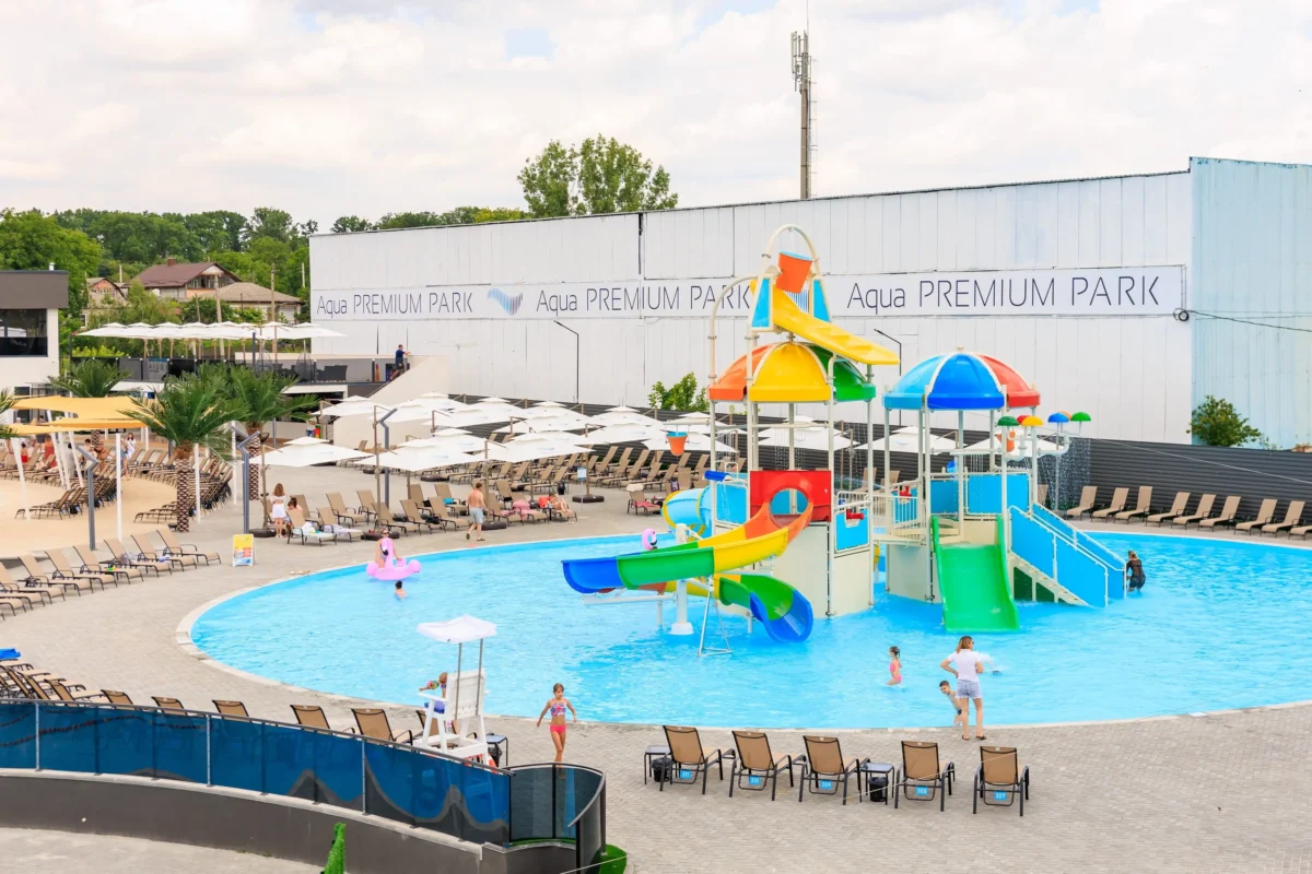 Water park pool area with colorful slides, loungers, and umbrellas at Aqua Premium Park.
