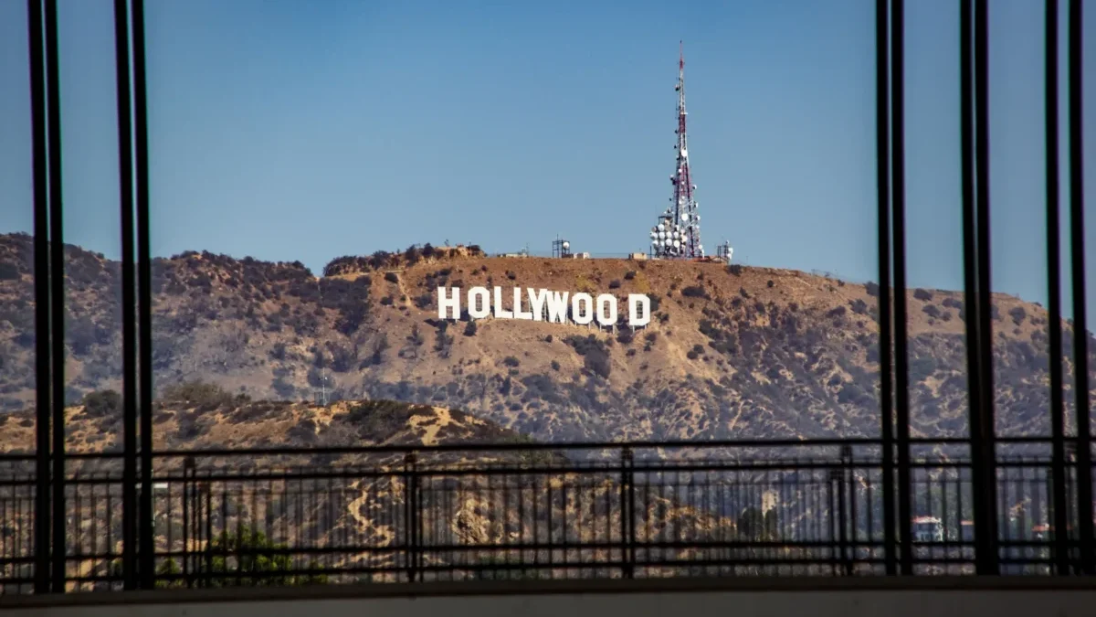Hollywood sign on a hill seen through a window with black vertical bars in the foreground.
