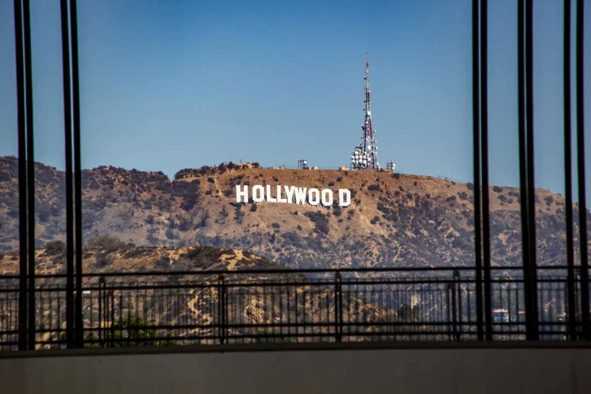Hollywood sign on a hill seen through a window with black vertical bars in the foreground.