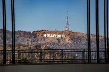 Hollywood sign on a hill seen through a window with black vertical bars in the foreground.