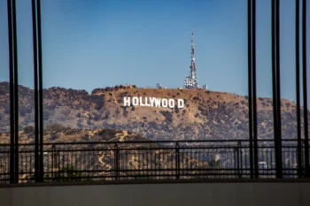 Hollywood sign on a hill seen through a window with black vertical bars in the foreground.