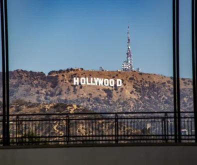 Hollywood sign on a hill seen through a window with black vertical bars in the foreground.