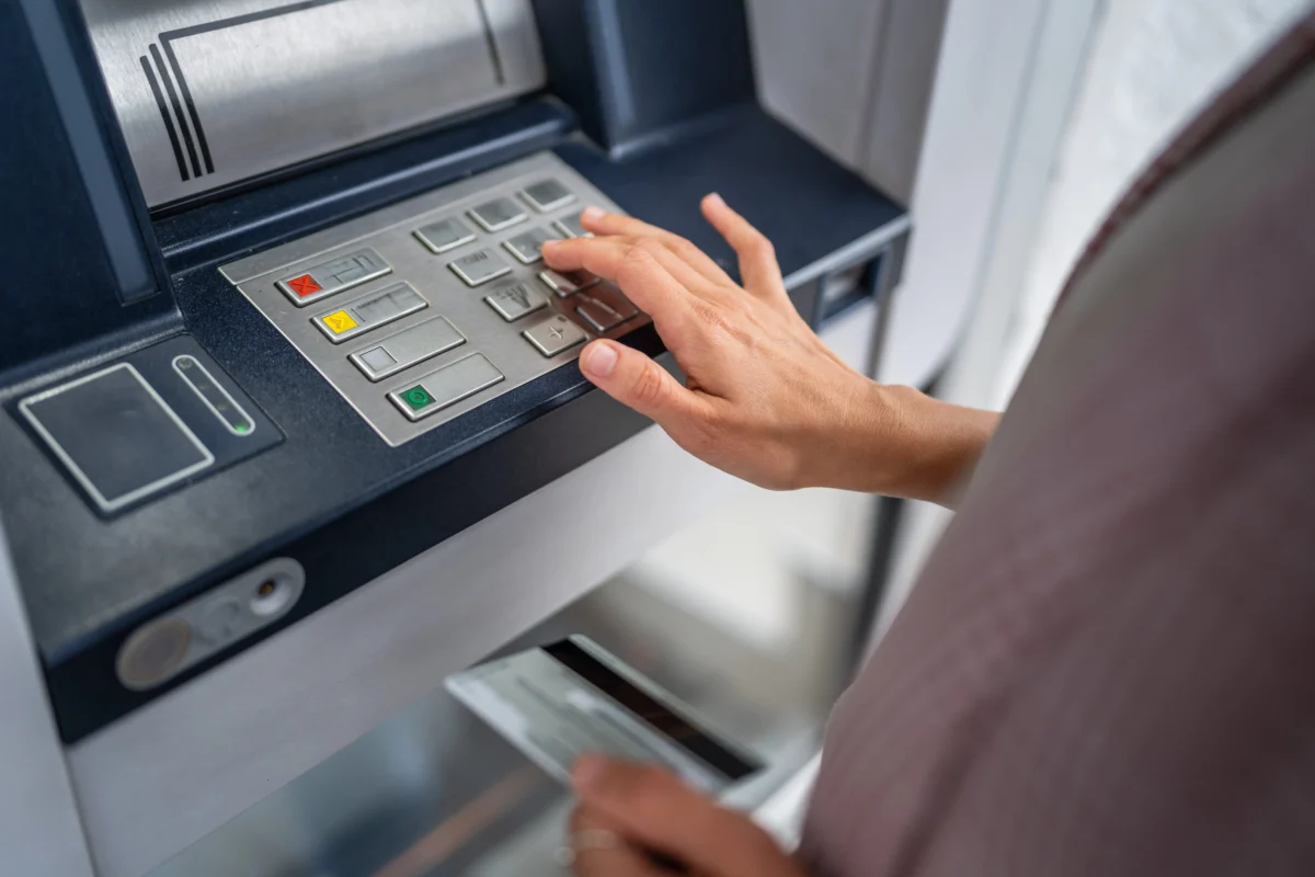 Person using an ATM, pressing the keypad to enter a PIN.
