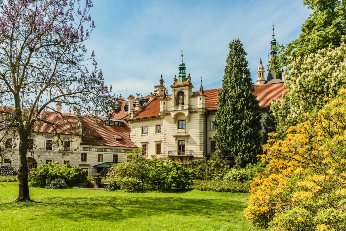 Zámek Průhonice je obklopený stromy.