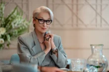 Meryl Streep sedí u stolu.