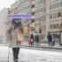 Stará žena jde s deštníkem po chodníku.