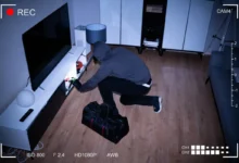 Person kneeling on a wooden floor, sorting and plugging in cables near a white entertainment unit in a living room.