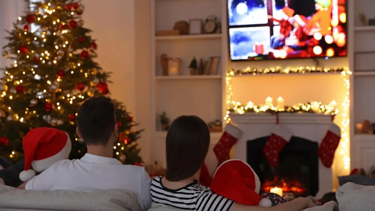 Rodina sedí u vánočního stromku a televizoru