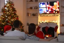 Rodina sedí u vánočního stromku a televizoru