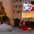 Rodina sedí u vánočního stromku a televizoru
