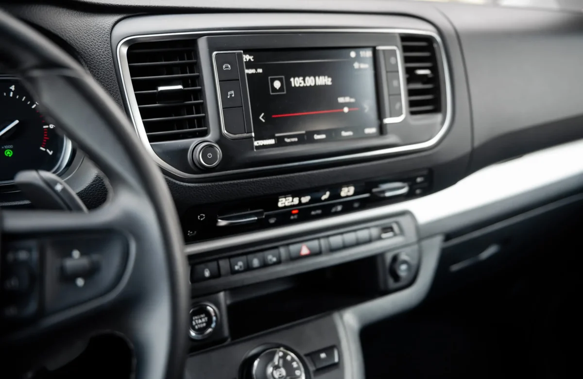 shutterstock_2594835287 1 | TVGURU.cz Center infotainment screen in a car showing a radio tuned to 105.00 MHz, with air vents and control knobs nearby.