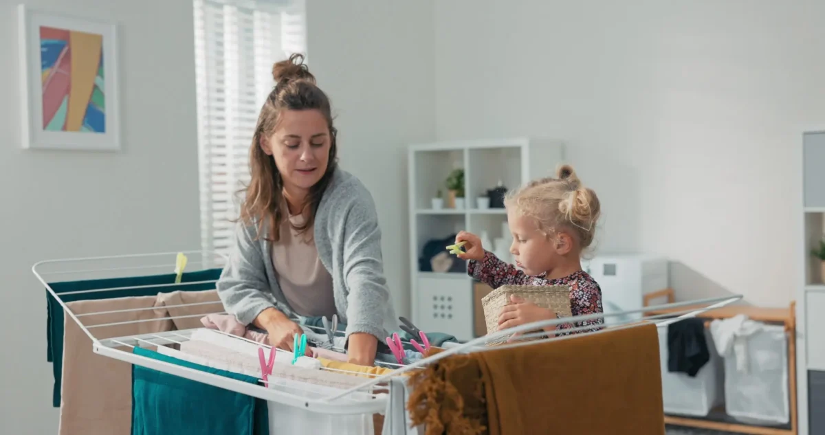 Vybělit prádlo lze jednoduchým způsobem. Zdroj: Shutterstock | TVGURU.cz Žena s dcerou věší prádlo