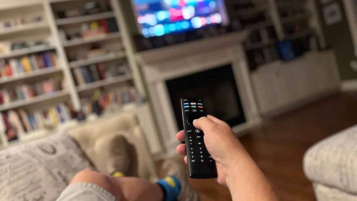 Muž ovladačem míří na televizi.